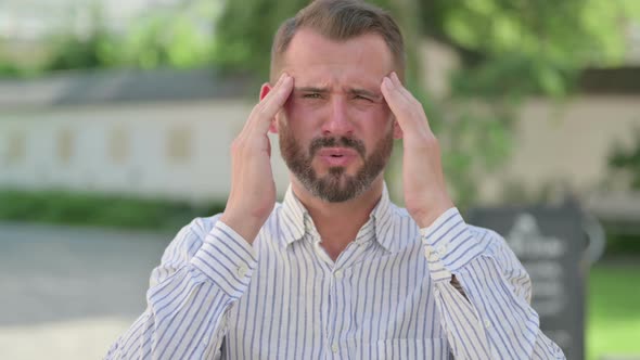 Outdoor Portrait of Middle Aged Man Having Headache