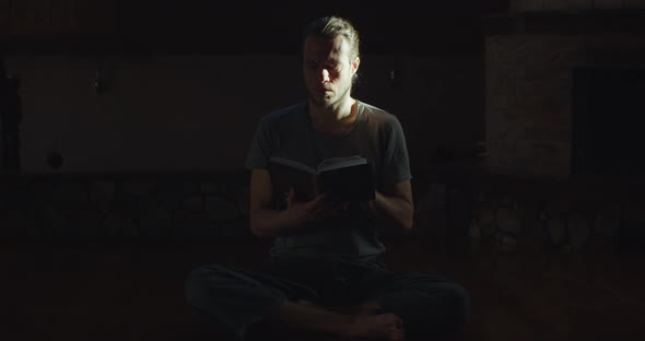 Pensive Man Reading Paper Book Indoors Enlightened By Sun Rays