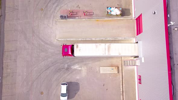 Aerial Shot of Truck with Attached Semi Trailer Leaving Industrial Warehouse/ Storage Building/ Load