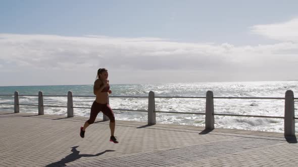 Sporty Caucasian woman exercising on a promenade on seaside