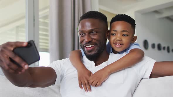 African american father and son taking a selfie with smartphone