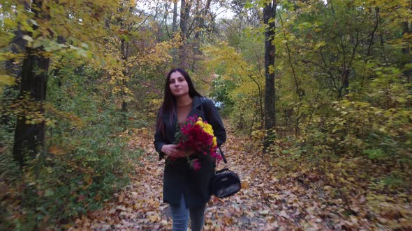 Girl with Flowers Walks in the Autumn Forest