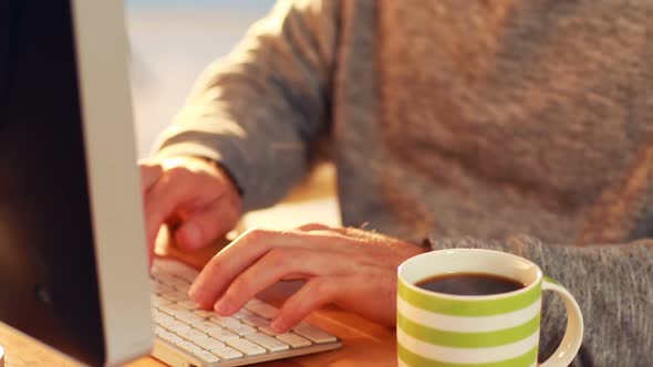 Business executive working on computer while having coffee