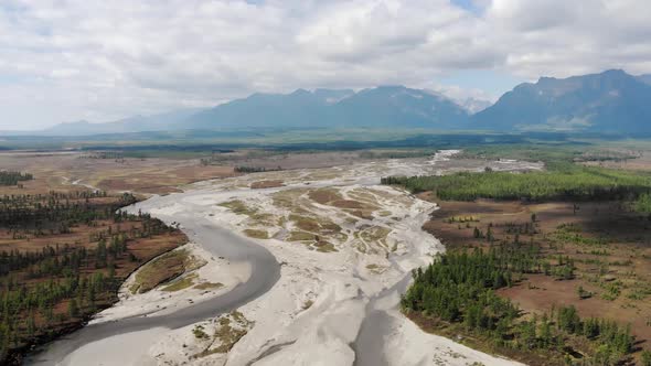 The Drone Flies Over the River. High Blue Mountains in the Background