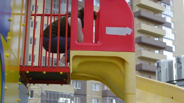 Young Boy Enjoying Playground Slide with Mom and Dad alt