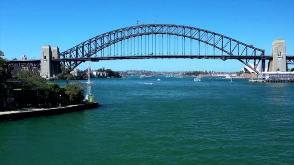 Drone over Sydney Harbour tracks along Sydney Harbour Bridge on beautiful sunny day