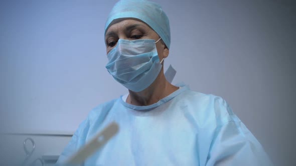 Mature Doctor Conducting Hard Responsible Surgery, Wiping Sweat From Forehead