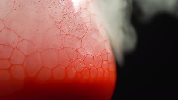 Closeup of Dry Ice Bubbling in a Glass with Red Blood on a Black Background.