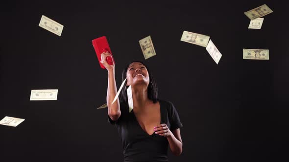 Mixed ethnicity woman shooting money out of a money gun.