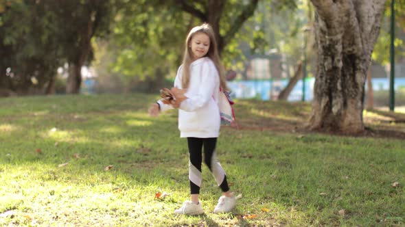 Little Girl Playing with Fallen Autumn Leaves