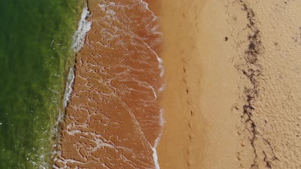 Aerial View Close-up Low Flight Over Sea Waves Rolling on the Golden Sandy Coast. Calm Surf Behind