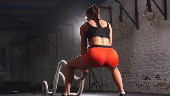 Powerful Attractive Muscular Woman Cross Fit Trainer Do Battle Workout with Ropes at the Gym. Slow