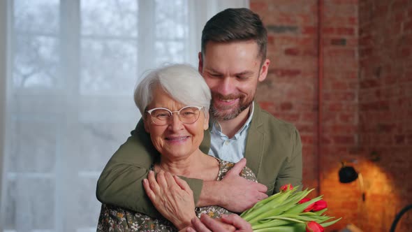 Caucasian Smartly Dressed Millennial Man Being Affectionate with His Elderly Pensioner Mother