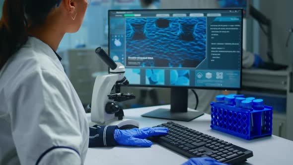 Biochemist Using Microscope and Writing at Computer Working in Equipped Lab