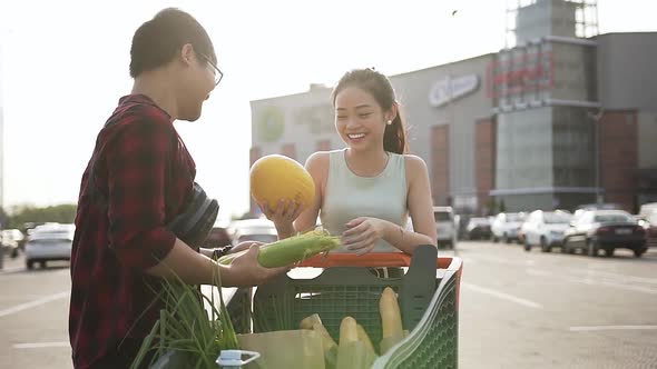 Smiling Asian Couple Satisfied Their Choice of Melon and Another Food in Market Cart