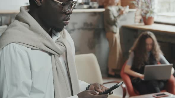 African-American Man Using Smartphone in Coworking Office