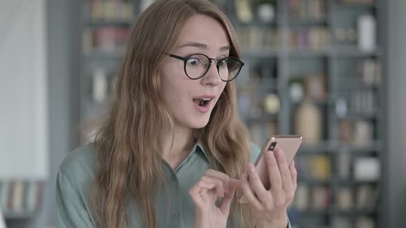 Portrait of Successful Young Woman Celebrating While Using Smartphone