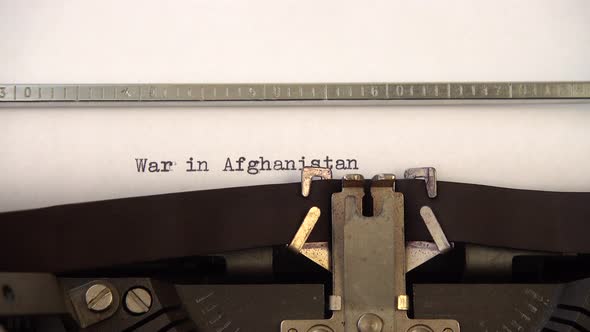 Typing phrase War in Afghanistan on retro typewriter. Close up.