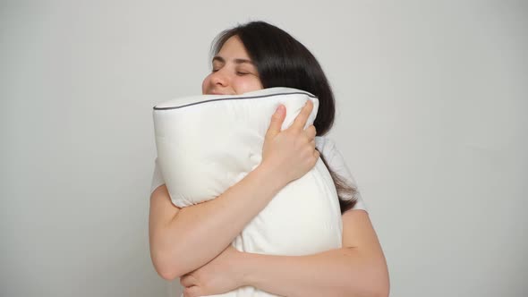 A Woman Hugs Her Favorite Orthopedic White Pillow and Smiles As She Looks Into the Camera