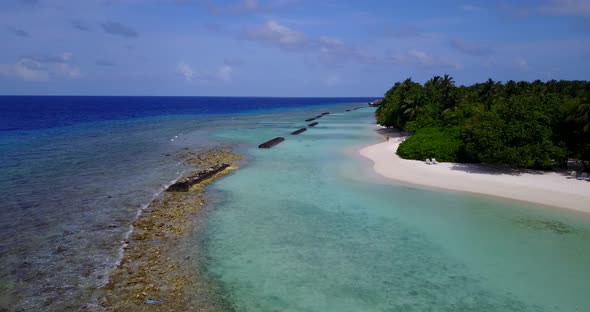 Wide overhead tourism shot of a sandy white paradise beach and turquoise sea background in colourful