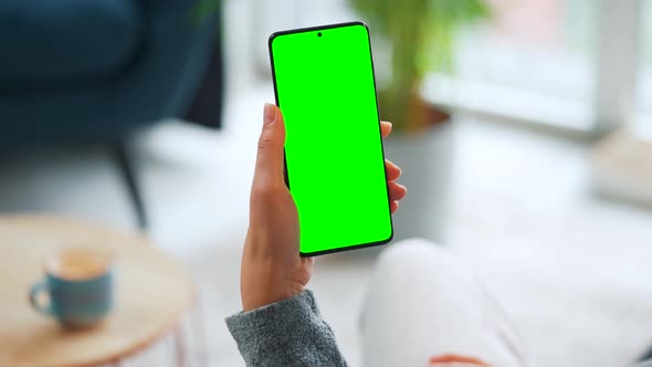 Woman at Home Using Smartphone with Green Mockup Screen in Vertical Mode