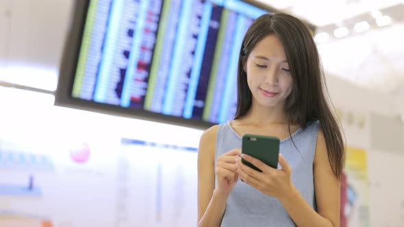 Woman looking at cellphone in airport 