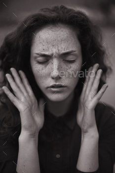 ting a state of anxiety, stress or mental tension. The young beautiful woman brought her tense palms to her face and closed her eyes in distress, as if trying to focus or free her mind.