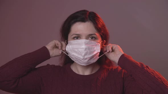 Woman Putting on Medical Protective Mask To Health Protection and Prevention From Virus on a Gray