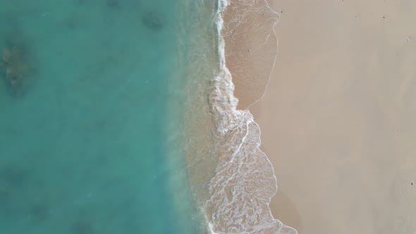 Ascending aerial top down showing beach, turquoise water and shore of Gili Meno Island.