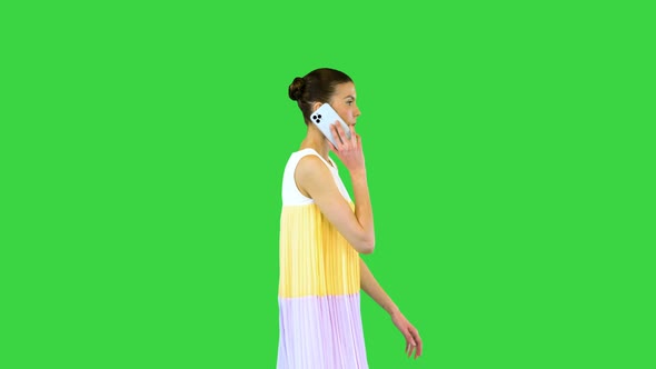 Young Beautiful Girl in Whiteyellow Dress Walks Talking on Mobile Phone on a Green Screen Chroma Key
