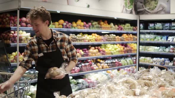 Busy Caucasian Young Worker Arranging Vegetables on Shelves at Grocery Shop