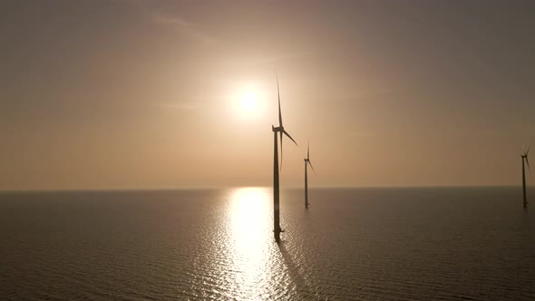 Dolly shot Wind farm on calm waters, Silhouette of Windmills spinning during sunset