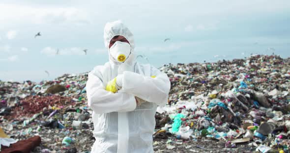 Portrait of Ecologist in Protective Suit Crosses Hands at the Polluted Land