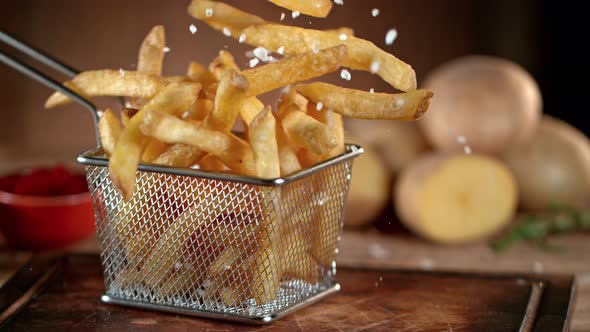 Super Slow Motion Shot of Falling Fresh French Fries on Wooden Table and Adding Salt at 1000Fps