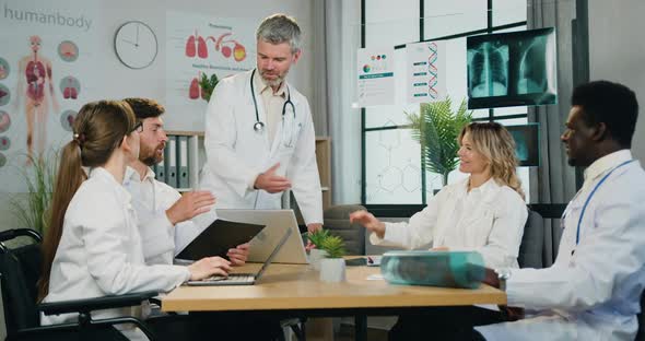 Bearded Head of Clinic Handshaking with His Confident Multicultural Male and Female coworkers