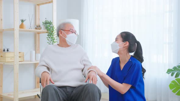 Asian young caregiver nurse take care senior older male on wheelchair at nursing home.