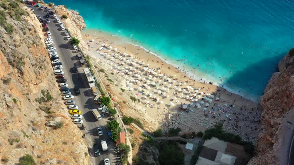 Aerial drone circling Kaputas Beach during sunset in Kas Turkey as cars drive looking for parking an