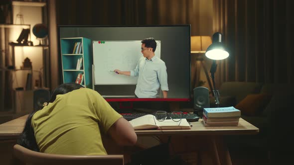 Girl Sleeping On The Table While Distance Learning With Online Teacher On Computer Screen From Home