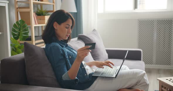 Slow Motion of Girl Shopping Online Holding Credit Card Using Laptop at Home