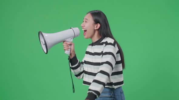 Side View Of Asian Woman Speaking On Megaphone In The Green Screen Studio