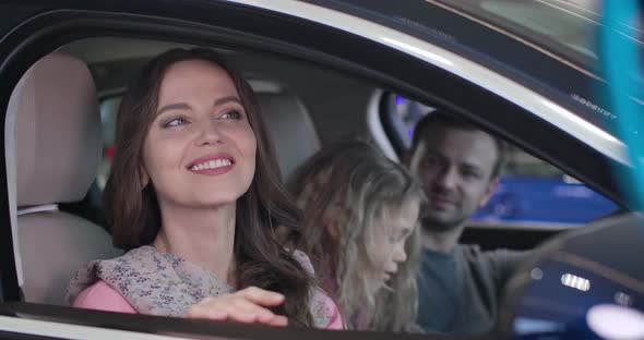 Close-up Portrait of Happy Young Caucasian Woman Sitting in Car with Family and Smiling