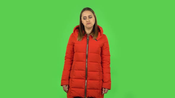 Lovely Girl in a Red Down Jacket Upset and Shrugging. Green Screen