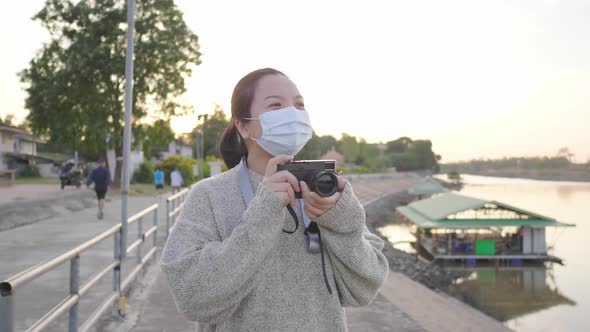 Asian woman standing and taking a picture by the river