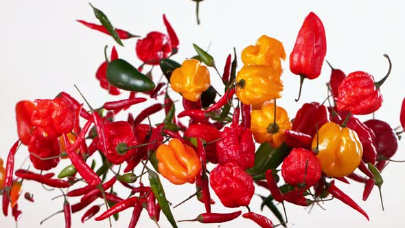 Super Slow Motion Shot of Flying Mixed Chilli Peppers Isolated on White Background at 1000Fps