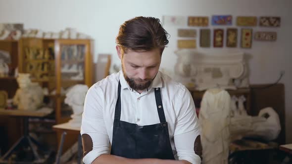 Master in white Shirt and Apron Standing with Folded Hands and Looking at Camera