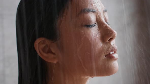 Chinese Young Lady Taking Shower Closing Eyes In Bathroom Indoors