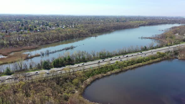 An aerial view over some reflective lakes during the day. The drone truck right along side the parkw