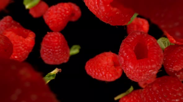 Super Slow Motion Detail Shot of Flying and Rotating Fresh Raspberries and Green Leafs at 1000Fps