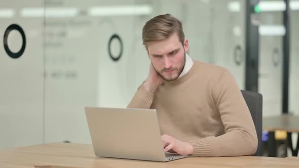 Creative Young Man with Laptop Having Neck Pain in Office