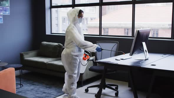 Cleaner wearing protective clothes sanitizing modern office space